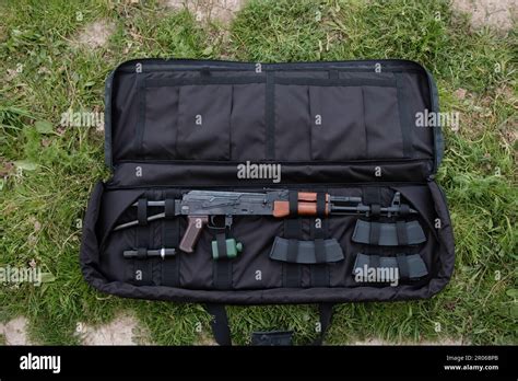 Uncovered gun case with AK-47, magazines, and flashlight lying on the ground black Stock Photo ...