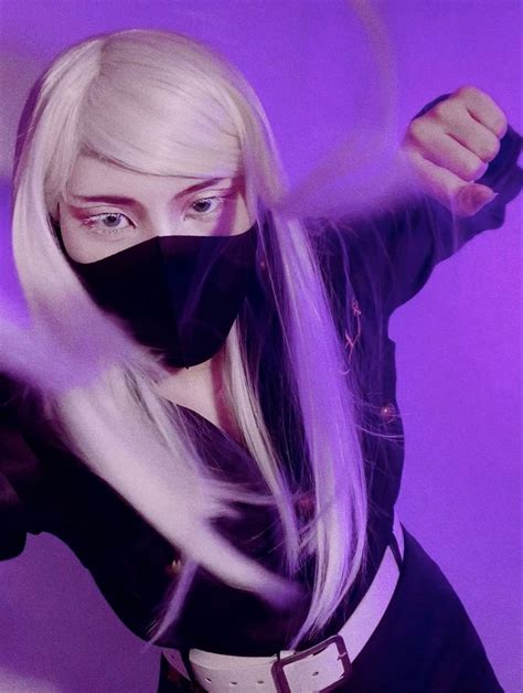 a woman with white hair wearing a black mask and holding her hands out in front of her face