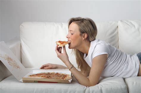 Premium Photo | Blonde woman eating pizza on the couch