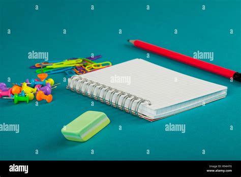 White notebook, pencil and colorful paper clips on blue background - school supplies concept ...