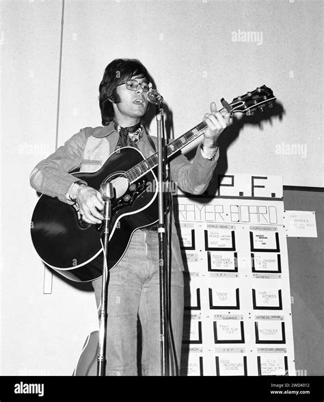 Cliff Richard playing guitar and singing at a charity event in a church ...