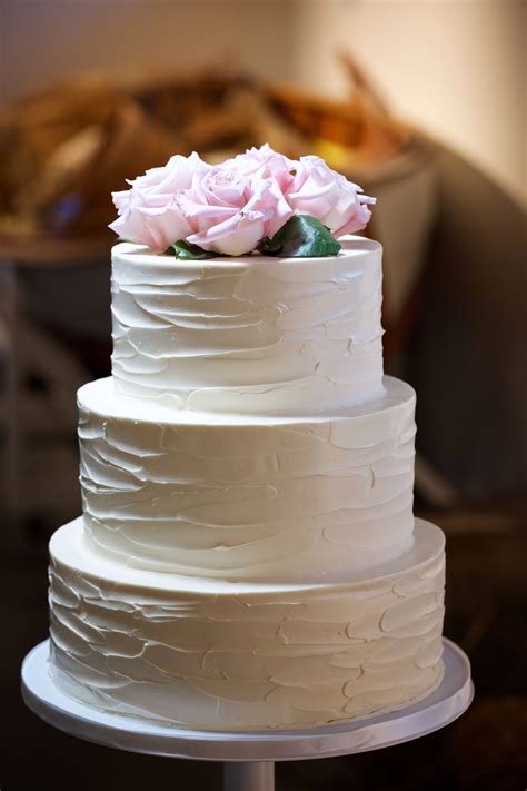 a three layer white cake with pink flowers on top