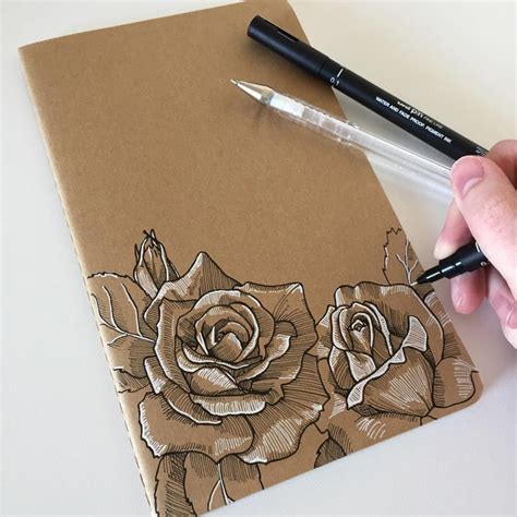 a person drawing flowers on a brown notebook