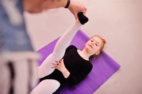 Premium Photo | Child - little cute red-haired girl ballerina performs stretching exercises in ...