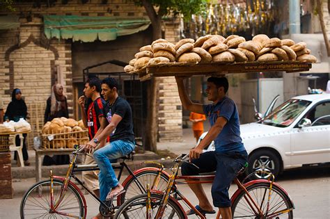 Starch Source - A bicycle bread delivery guy carries a rack of fresh bread on his head. - Cairo ...