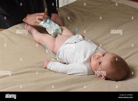 changing the diaper on the baby who is lying in bed Stock Photo - Alamy