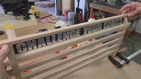 two hands holding up a wooden sign that says challenge your limits on the back of a bench