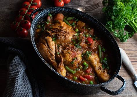 Brown Chicken Stew with Vegetables, Potatoes and Legumes in a Old Fashioned Pot on Wooden Table ...