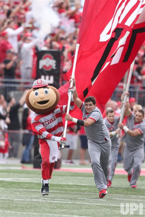 Photo: Ohio State Buckeyes mascot Brutus Buckeye and cheerleader run onto the field ...