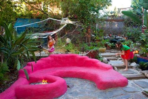 a pink bench sitting in the middle of a garden next to a fire pit and trees