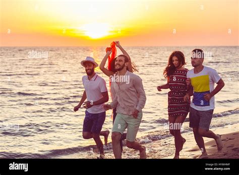 Group of happy young people is running on background of sunset beach and sea Stock Photo - Alamy