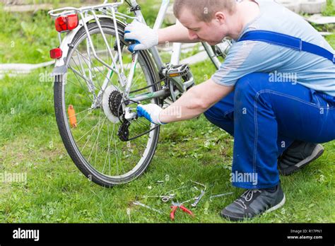 man is fixing the bike. Adjust gears Stock Photo - Alamy