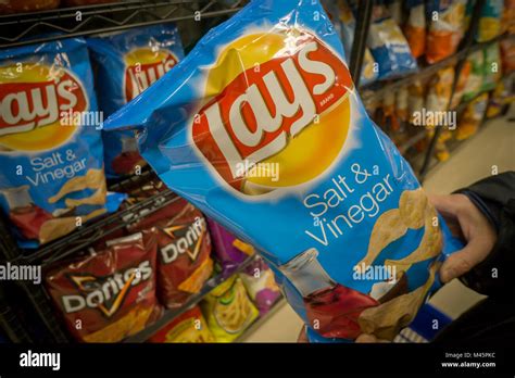 A shopper chooses a bag of PepsiCo Frito-Lay brand potato chip snacks ...