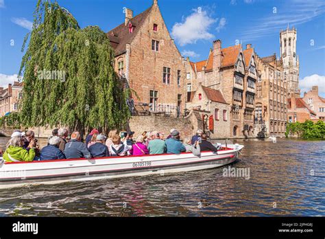 Tourists enjoying a guided boat tour around the canals of Bruges ...