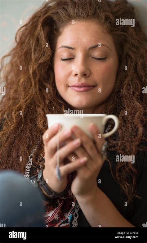 Portrait of woman sitting on bed with tea cup and closed eyes Stock Photo - Alamy