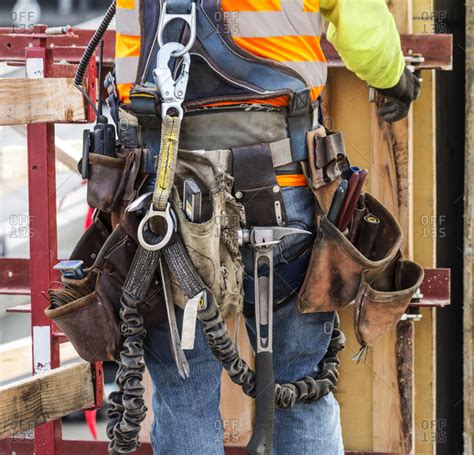 Hispanic worker wearing tool belt at construction site stock photo - OFFSET