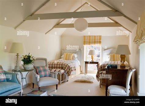 Attic twin bedroom with beamed ceiling, yellow striped matching blinds and cushions and blue ...