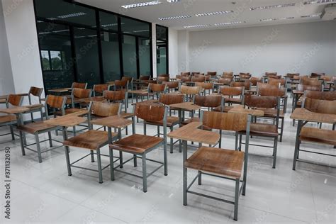 Empty school classroom with many wooden chairs. Wooden chairs in classroom. Empty classroom with ...