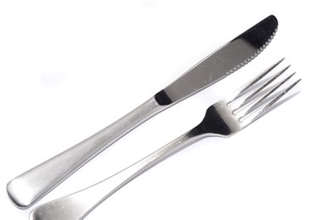 Silver knife and fork diagonally on white - Free Stock Image