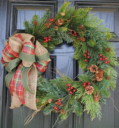 a christmas wreath with pine cones, berries and green ribbon hanging on ...