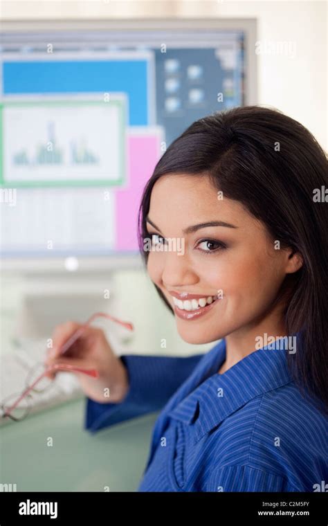 Smiling Hispanic woman at office desk with computer monitor Stock Photo - Alamy