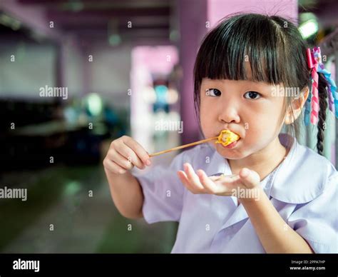 Asian girl child eating a crispy wonton Stock Photo - Alamy