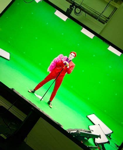 a man dressed in red and pink is standing on a green screen