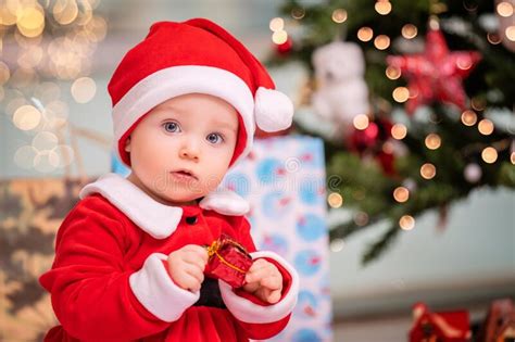An Adorable Kid Dressed As Santa Claus Plays Near a Decorated Christmas ...