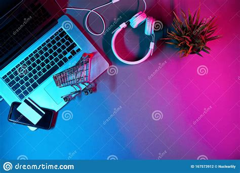 Laptop with Headphones, Custumers Trolley, Phone and Payment Card on the Table in Modern Neon ...