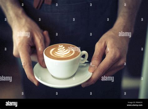 barista serving a beautiful flat white with latte art, close up with hands Stock Photo - Alamy