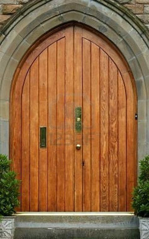 An old stone arched doorway with wooden doors and brass accessories. | Arch doorway, Wooden ...