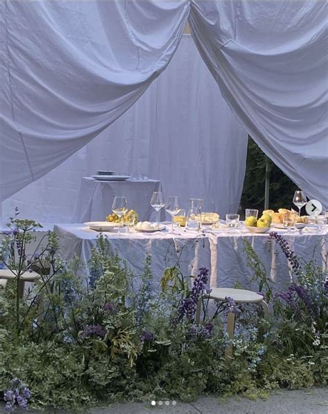 an outdoor table set up with flowers and fruit for a formal dinner or party event