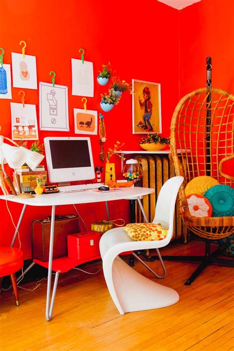 a room with orange walls and pictures on the wall, including a laptop computer sitting on top of ...