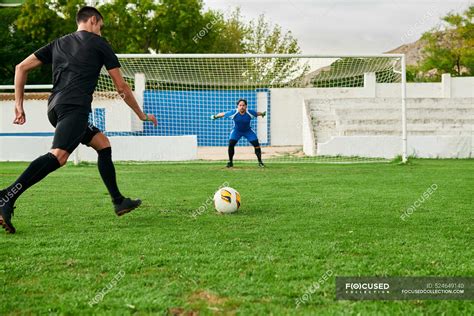 A soccer player takes a penalty kick against a goalkeeper — stadium ...