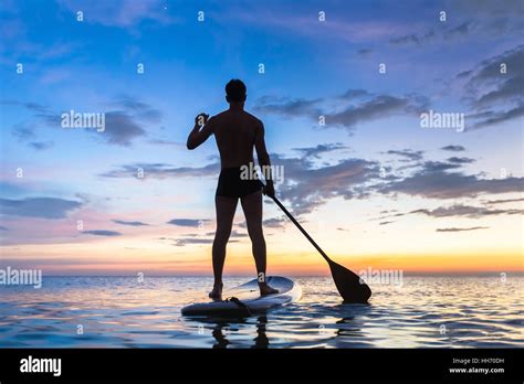 Silhouette of stand up paddle boarder paddling at sunset on a flat warm quiet sea Stock Photo ...