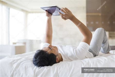 Chinese man lying down with digital tablet on bed — Domestic Life ...