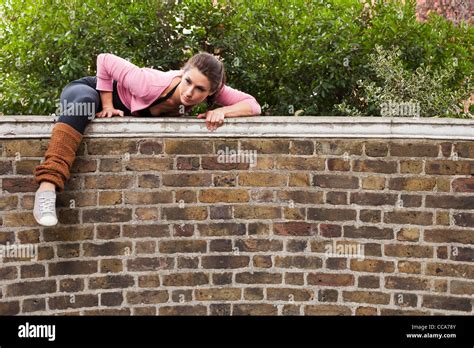 Woman climbing over over wall Stock Photo - Alamy