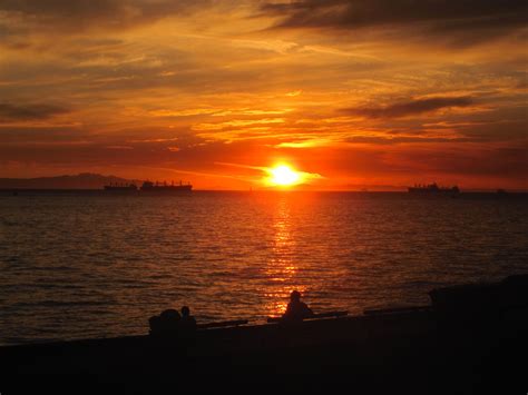 the sun is setting over the ocean with ships in the distance