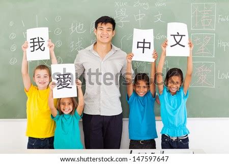 Friendly Male Chinese Teacher With Group Multiracial Primary Students Holding Papers Saying I ...