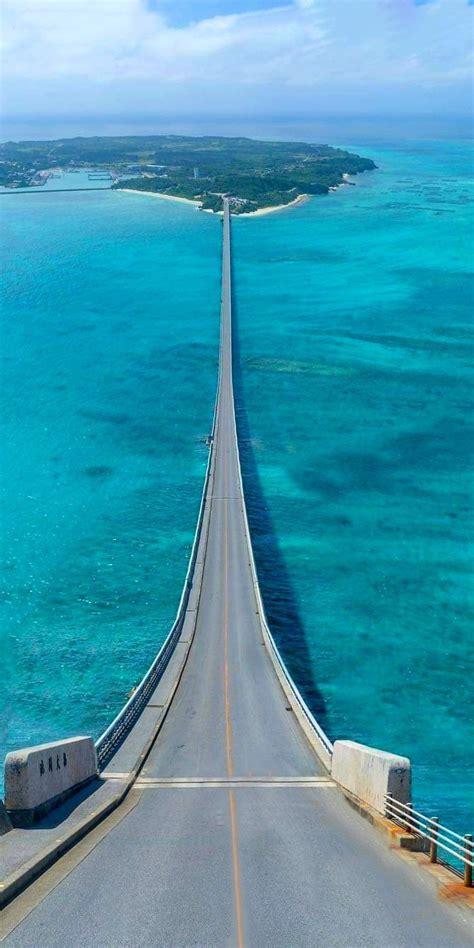 an aerial view of a long bridge spanning the ocean with blue skies and water in the background
