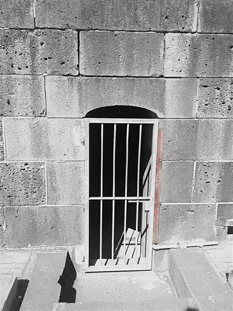 a black and white photo of a jail cell door with bars on it's sides