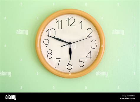 Clock hanging on wall and showing current time Stock Photo - Alamy