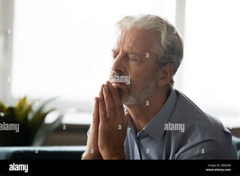 Hopeful old man hold hands in prayer praying at home Stock Photo - Alamy