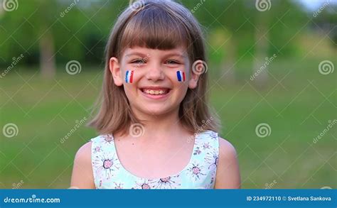 Adorable Little Girl Smile at Camera with Cheeks Painted in Flag of France. Bastille Day on July ...