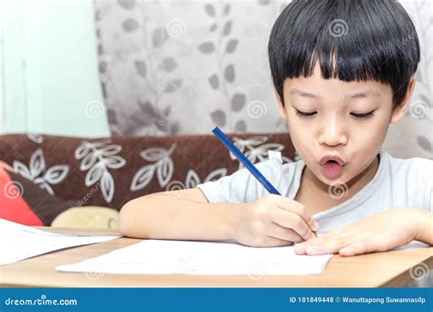 Little Boy Writing Homework on Wooden Table at Home. Kid Learing and Writing Alphabet Looking ...