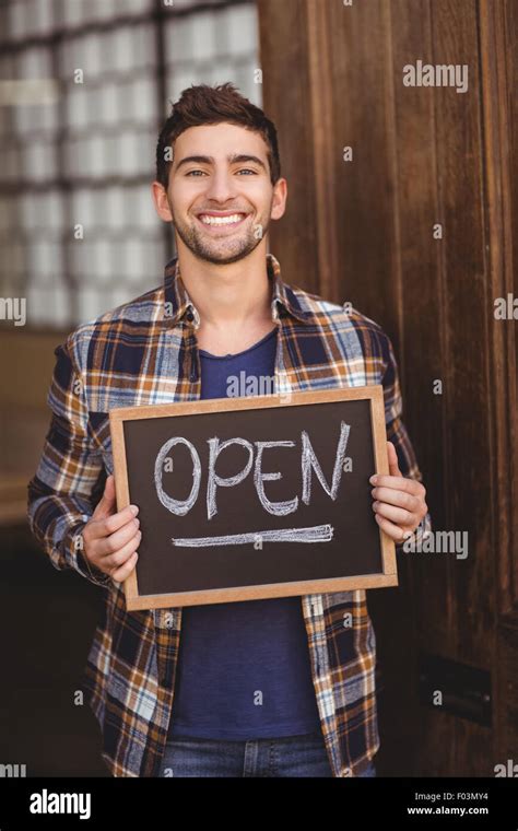 Smiling casual waiter showing chalkboard with open sign Stock Photo - Alamy