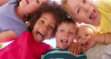 Happy Mixed Racial Group Of Friendly Children Sitting In The Sun Laughing Together, Panning In ...