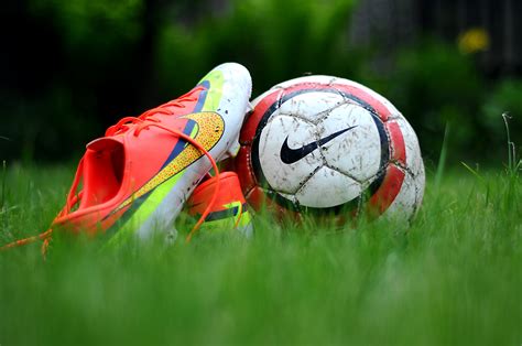 close up photography of Nike soccer cleats and soccer ball on green grass field during daytime ...