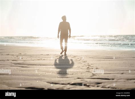 Man walking towards sea at beach Stock Photo - Alamy