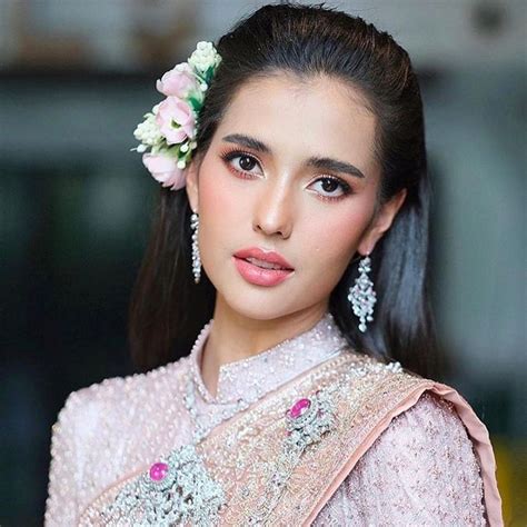 a woman with long dark hair wearing a pink dress and flower in her hair ...